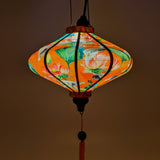 Glowing UFO shaped Vietnamese lantern featuring cranes and lotus flowers with an orange hue.