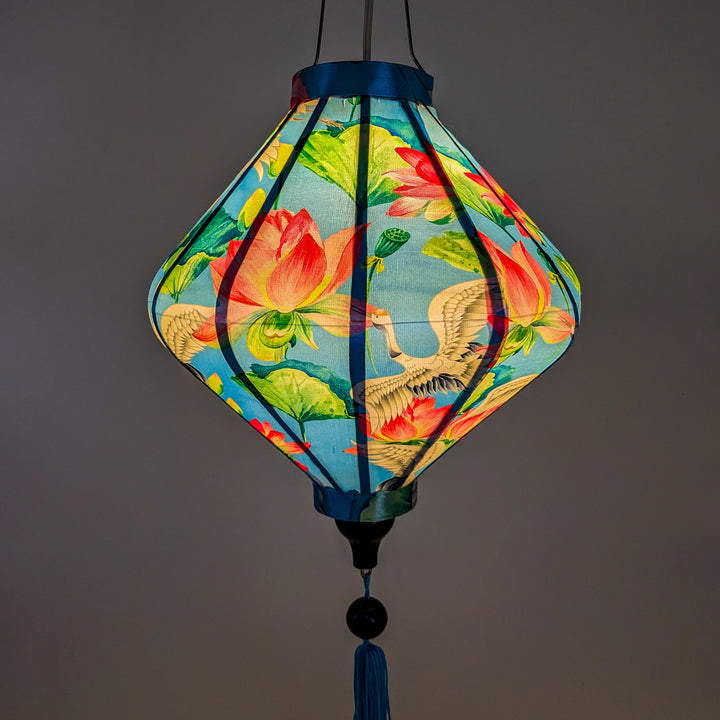 Close up of a glowing Lozenge shaped lantern with cranes and lotus flowers creating a beautiful soft blue hue.