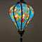 Glowing Vietnamese silk lantern with lovebirds perched in a tree on blue background.
