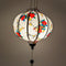 A glowing round Vietnamese silk lantern adorned with a delicate floral pattern featuring vibrant red and yellow blossoms, handmade in Hoi An, Vietnam.