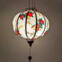 A glowing round Vietnamese silk lantern adorned with a delicate floral pattern featuring vibrant red and yellow blossoms, handmade in Hoi An, Vietnam.