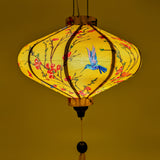 UFO shaped lantern being lit from inside with little hummingbirds mid-flight hunting nectar from orange and pink flowers creating a gorgeous glowing yellow hue.