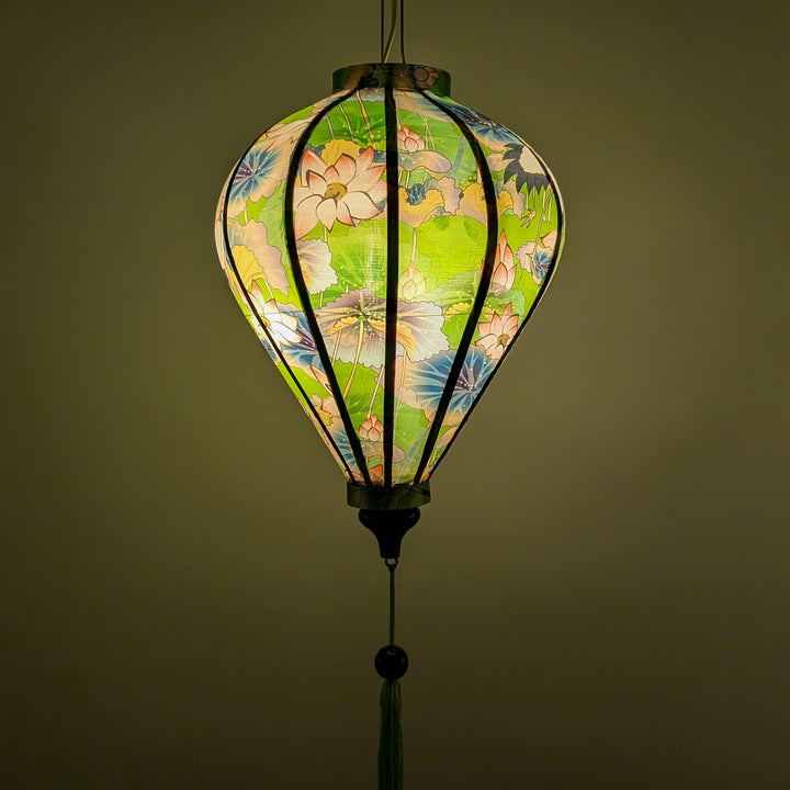 Vietnamese silk lantern with open bill birds and lotus flowers on a green background creating a green glow.