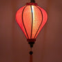 A glowing balloon shaped lantern handmade with orange jacquard silk fabric.
