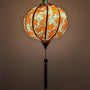 Glowing Vietnamese silk lantern with orange koi fish and lotus flowers with gold background.