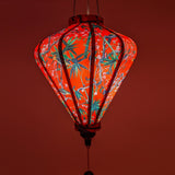 Glowing Diamond shape lantern lit from inside by an outside light source beaming with a warm red glow.