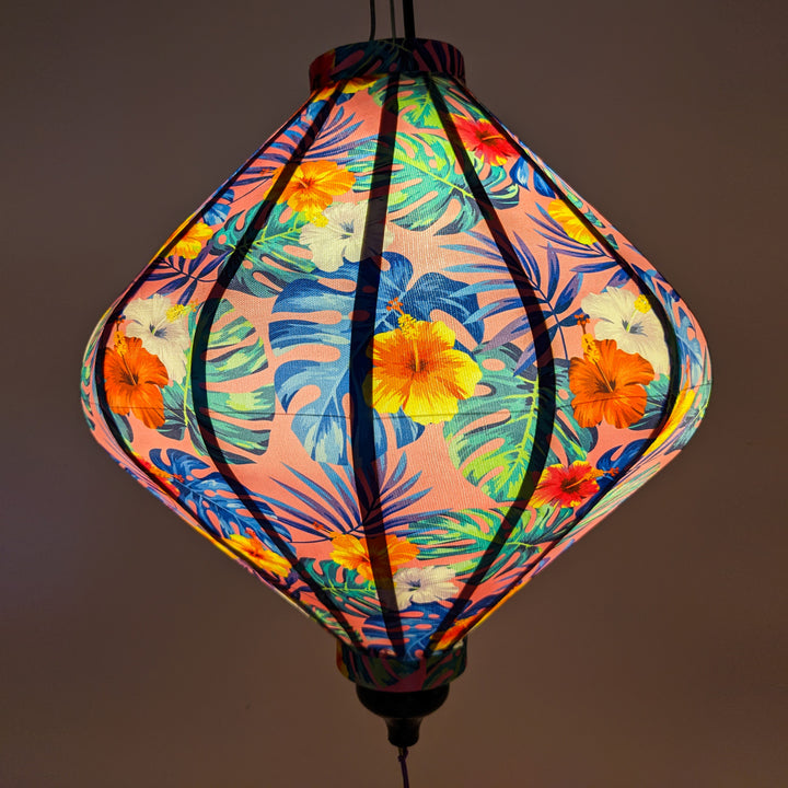 Close up of a lit up Lozenge shaped lantern featuring hibiscus flowers and and a soft pink glow.