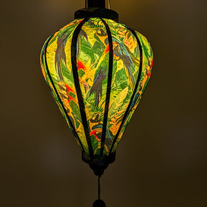 Glowing Vietnamese lantern with a collage of parrots surrounded by leaves.