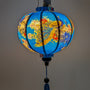Glowing round Vietnamese silk lantern with vivid peacocks and blossoms in blue, pink and red on a deep blue background. 