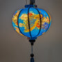 Glowing round Vietnamese silk lantern with vivid peacocks and blossoms in blue, pink and red on a deep blue background. 