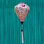 A balloon shaped lantern with white tassel hanging in front of a painted blue wall featuring pink and black cranes among lush green foliage and delicate flowers. 