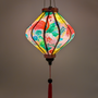 Glowing lozenge shape lantern with tropical flamingo paradise print, with intricate floral details in shades of gold, purple featuring bold pink flamingos surrounded by lush tropical flowers.