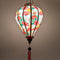 A glowing balloon shaped lantern with a print of pink flamingos and bird of paradise flowers on a light pink background.