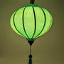 Round Vietnamese lantern with glowing mint green hue.