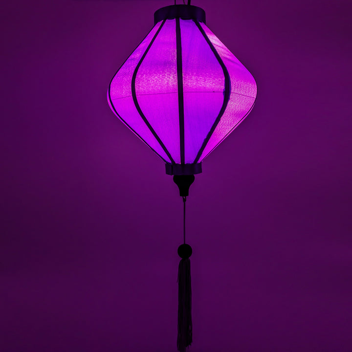 Glowing Lozenge shaped light purple plain silk Hoi An Vietnamese Lantern lit up with a lightbulb.