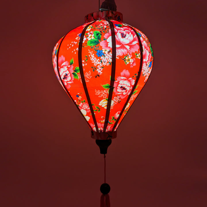 Handmade floral-patterned red silk lantern, by Hoi An’s artisanal craftsmanship for cozy lighting.
