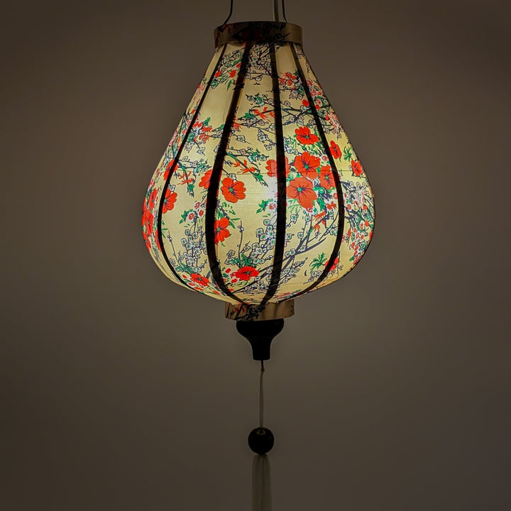 Glowing garlic shape Vietnamese silk lantern with red flower blossoms on cream silk background.