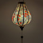 Glowing garlic shape Vietnamese silk lantern with red flower blossoms on cream silk background.