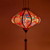 Glowing UFO shaped lantern with print of yellow flowers and firecrackers creating a warm red glow.