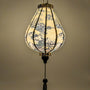 Glowing Garlic shaped lantern featuring a print of mountains, trees, temples, men in boats, and large rocks. A beautiful glow created by a palette of light pinks and purples against a serene creamy background.