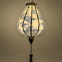 Glowing Garlic shaped lantern featuring a print of mountains, trees, temples, men in boats, and large rocks. A beautiful glow created by a palette of light pinks and purples against a serene creamy background.