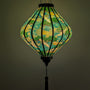 Glowing lantern with green and yellow patterns on a teal featuring cranes and geometric patterns