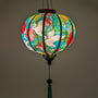 Glowing round Vietnamese silk lantern featuring vibrant cranes & floral print on blue.