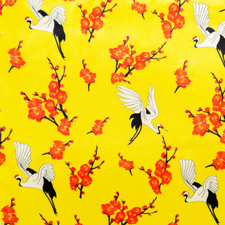 Polyester silk fabric with a print of cranes surrounded by orange flowers on a bright yellow background.