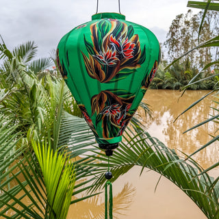 Balloon shaped lantern with flaming flowers in bloom on a vibrant green.
