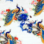 Polyester silk fabric with large, flamboyant peacocks surrounded by red, blue, and pink flowers on a white background. 