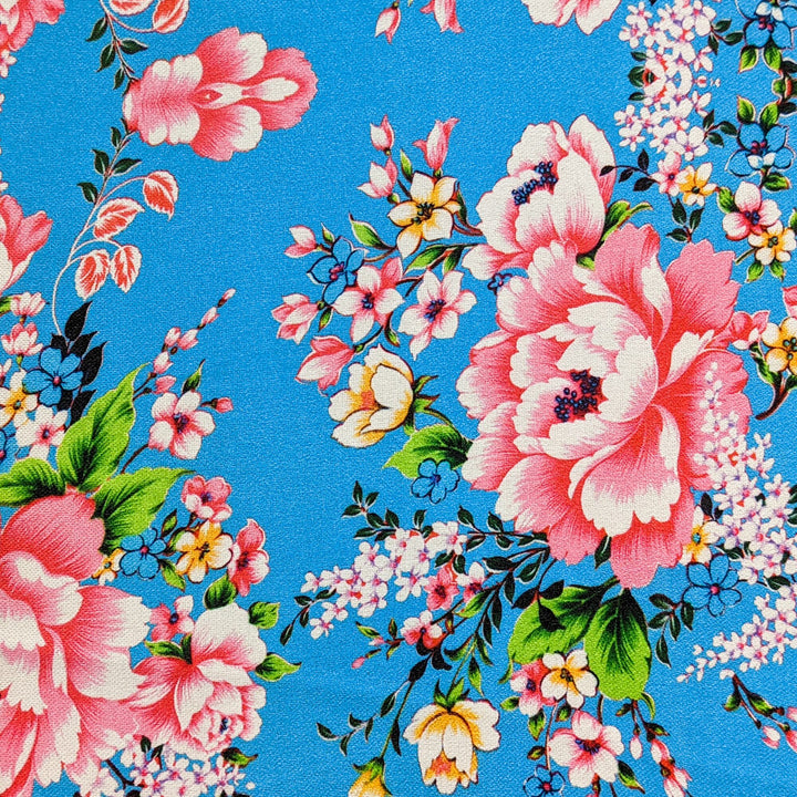 Polyester silk fabric with pink and yellow roses on a light blue background.