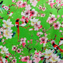 Polyester silk fabric with red-headed woodpecker birds sitting in cherry blossom trees on a bright green background.