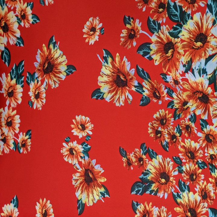 Polyester silk with bold red fabric adorned with vibrant sunflower patterns. 