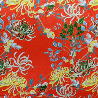 Polyester silk fabric with delicate chrysanthemum flowers in yellow, green, brown, on a burnt orange red background. 