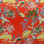 Polyester silk fabric with delicate chrysanthemum flowers in yellow, green, brown, on a burnt orange red background. 